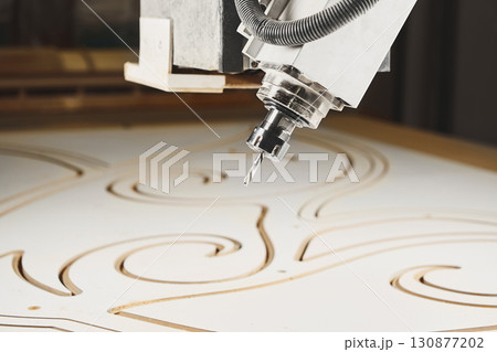 four-axis numerically controlled woodworking machine cuts out complex lines on the canvas. CNC, computer control. 130877202