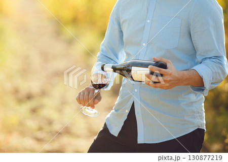 Faceless Skilled Sommelier Pouring Wine on Grape Plantation with a free Copy Space Faceless Skilled Sommelier Pouring Wine on Grape Plantation with a free Copy Space 130877219