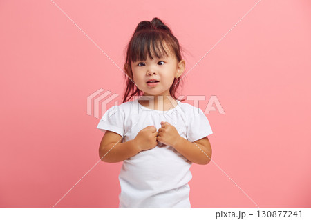 Puzzled little girl with her hands folded in front of her, facing a difficult choice, unable to make a decision standing on a pink isolated background. 130877241