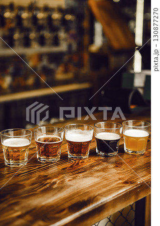 Variety of Craft Beers Sets Displayed on Wooden Bar Counter in Pub Setting 130877270