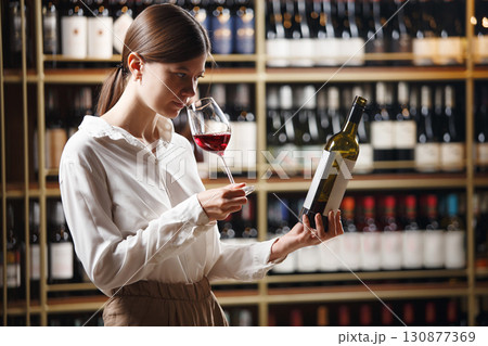 Professional caucasian woman sommelier checking wine quality and compare the data for taste. 130877369