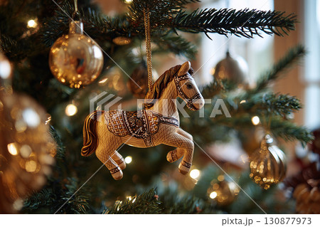 Close-up of a Christmas tree decorated with a toy horse, baubles and festive lights indoors. 130877973