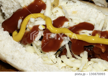 Close up of mustard and ketchup tomato sauce on a hot dog and cheese roll 130878993