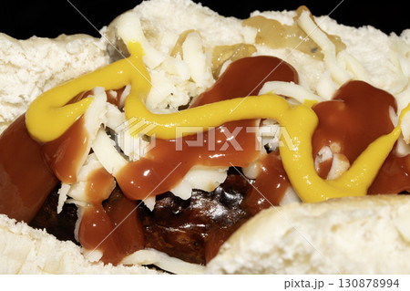 Close up of mustard and ketchup tomato sauce on a hot dog and cheese roll 130878994
