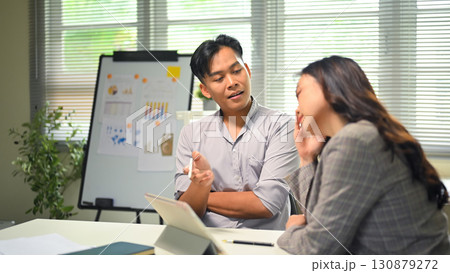 Business colleagues discussing ideas while using a digital tablet during office meeting 130879272