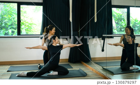 Yoga instructor guiding student in a seated twist pose during a private class Yoga instructor guiding student in a seated twist pose during a private class 130879297