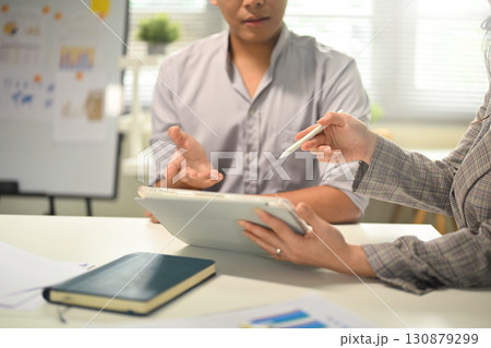 Business colleagues discussing ideas while using a digital tablet during office meeting Business colleagues discussing ideas while using a digital tablet during office meeting 130879299