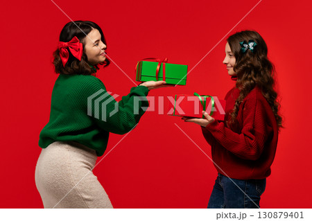 Mum and teenage daughter share red and green boxes, smiling Mum and teenage daughter share red and green boxes, smiling 130879401