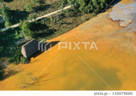 Aerial view of sinking village house in the middle of toxic mine decanting lake 130879666