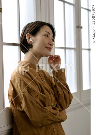 窓際で音楽やラジオを聴いている女性 窓際で音楽やラジオを聴いている女性 130879977