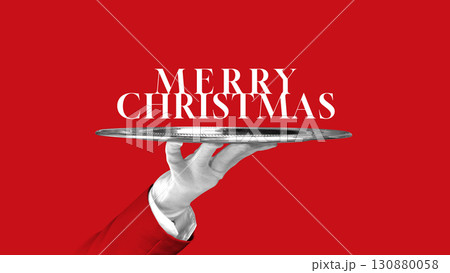 Creative collage. Merry Christmas text on silver tray with white glove hand and red festive background 130880058