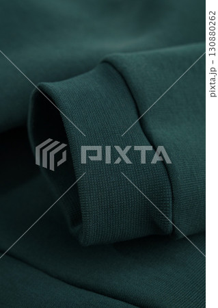 Hoodie texture. Close-up of dark green sweatshirt sleeve. Textile warm fabric macro background. 130880262