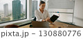 A businesswoman is diligently reviewing important documents within a modern office environment 130880776