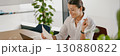 A Professional Woman Fully Engaged in Her Work Utilizing a Laptop and Various Documents 130880822