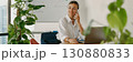 A professional businesswoman is working in a modern office environment while making a phone call 130880833