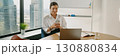 A professional woman is actively engaged with her mobile device while in the office environment 130880834