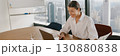 A professional businesswoman is diligently analyzing data within a modern office environment 130880838