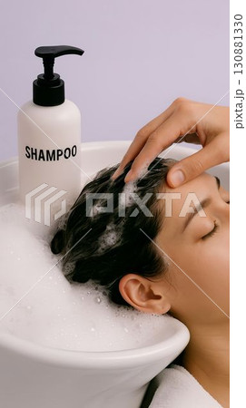 Young woman enjoying a relaxing shampoo treatment in a spa-like environment with bubbles 130881330