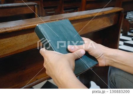 man holding a green prayer book in church man holding a green prayer book in church 130883200