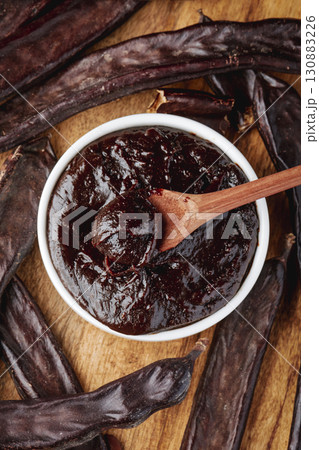 bowl of carob spread with spoon surrounded by pods bowl of carob spread with spoon surrounded by pods 130883226