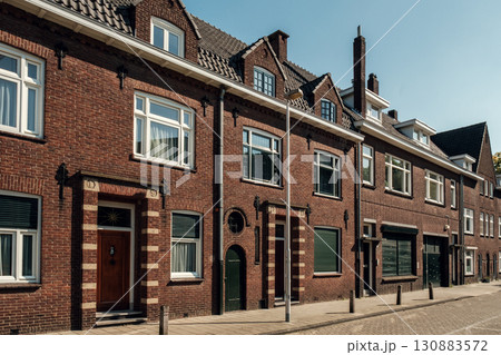 Charming brick houses with large windows and unique architectural details in urban setting 130883572