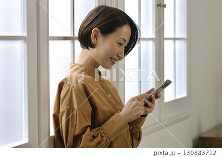 窓際でスマホを操作する女性 窓際でスマホを操作する女性 130883712