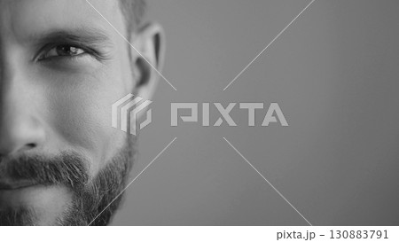 Extreme close-up, headshot half face of a confident young man 30s. Advertisement of skin care, facial care products for men. Isolation background, slow motion, copy space. Black white image. 130883791