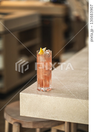 Pink cocktail in tall glass with lemon and ice 130883907
