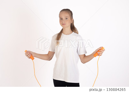 A young girl stands holding a jump rope, ready for exercise 130884265