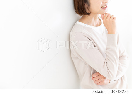 窓際の白壁にもたれて楽しそうに笑うカジュアルのミドル女性 窓際の白壁にもたれて楽しそうに笑うカジュアルのミドル女性 130884289