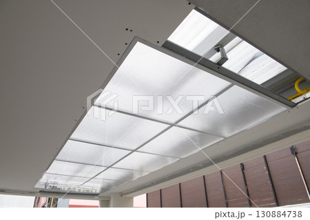 Focused detail on ceiling light installation during house renovation project. construction work shows new electric fixture and panel getting fitted with precision 130884738