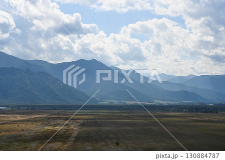 Cumulus clouds running over a valley and mountain landscape 130884787