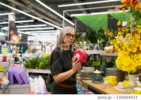 Woman shopping in a modern store, evaluating home decor items during a bright afternoon 130884933