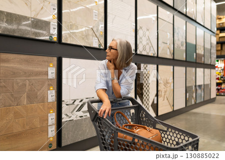 Woman shopping for tiles in a home improvement store during the afternoon, contemplating different 130885022