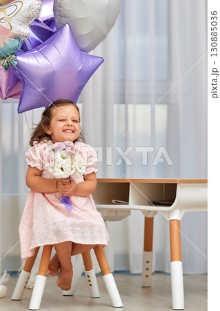 Cute little child girl in pink dress with flowers and pink purple balloons. Birthday concept. Cute little child girl in pink dress with flowers and pink purple balloons. Birthday concept. 130885036