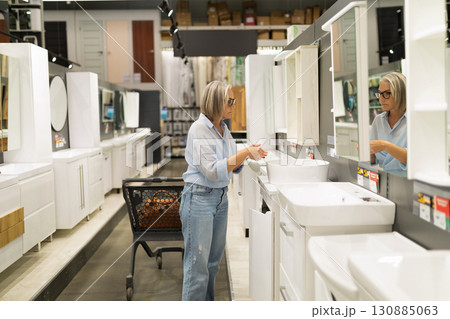 Woman examines bathroom vanities in a home improvement store while shopping in the afternoon 130885063