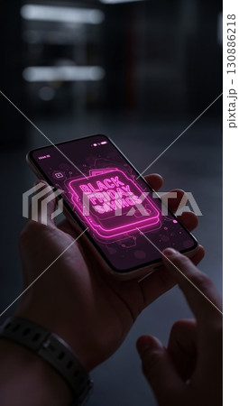 A person's hands hold a modern smartphone showcasing a vivid pink neon "Black Friday Savings" graphic, with a finger ready to interact on a blurred dark background. A person's hands hold a modern smartphone showcasing a vivid pink neon "Black Friday Savings" graphic, with a finger ready to interact on a blurred dark background. 130886218