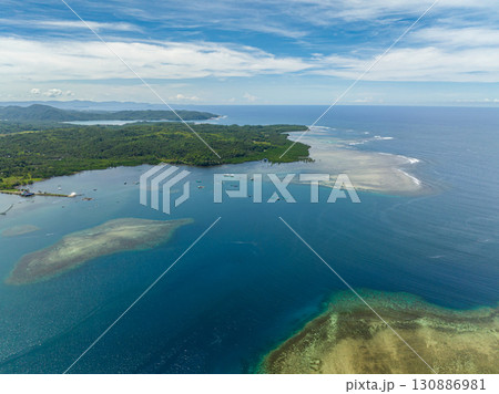 Tropical island and barrier reefs with corals, turquoise water, blue sea. Mindanao, Philippines. Seascape. Tropical island and barrier reefs with corals, turquoise water, blue sea. Mindanao, Philippines. Seascape. 130886981