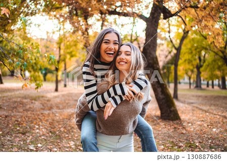 Joyful moments between friends in vibrant autumn park filled with leaves Joyful moments between friends in vibrant autumn park filled with leaves 130887686