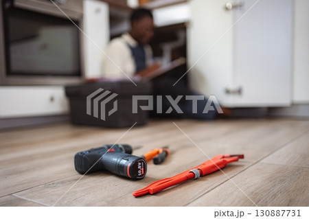 Plumber fixing kitchen sink using tools and writing notes 130887731