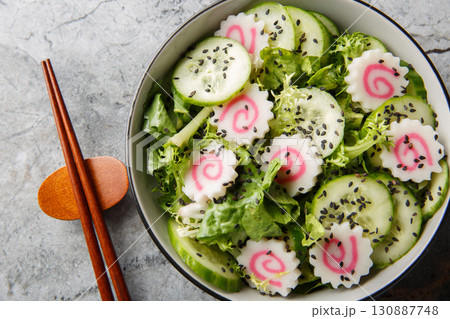 Low calorie Japanese salad with narutomaki fish roll, cucumber, lettuce and sesame dressing close-up in a bowl. horizontal top view 130887748