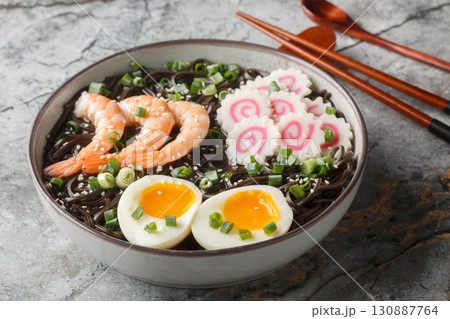 Tasty boiled Soba noodles with shrimp, narutomaki, green onion and egg close-up in a bowl. Horizontal 130887764