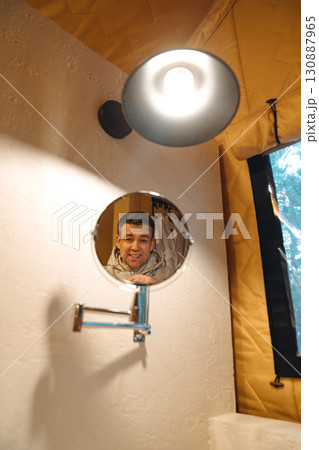 Lamp and round mirror in the bathroom in the tent house in the glamping. 130887965