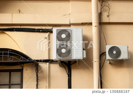Air conditioners on the facade of yellow historical house. An air ventilation and cooling system. 130888187