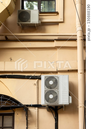 Air conditioners on the facade of yellow historical house. An air ventilation and cooling system. 130888190