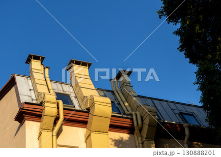 building with three chimneys on the roof. chimneys are yellow and the roof is brown.  130888201