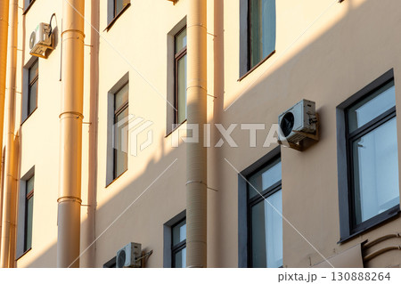 Air conditioners on the facade of yellow historical house. An air ventilation and cooling system. 130888264
