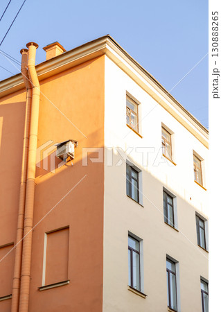 Air conditioners on the facade of a yellow house against a blue sky. An air ventilation. 130888265