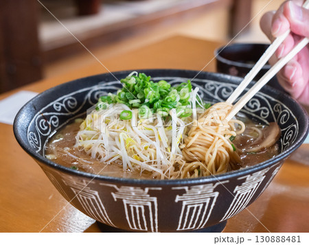 ネギともやしたっぷりのとんこつ醤油ラーメン。麺を箸あげしてる様子。 130888481