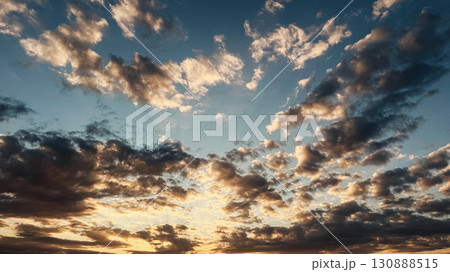 Dramatic sunset sky filled with scattered clouds illuminated by warm golden light Dramatic sunset sky filled with scattered clouds illuminated by warm golden light 130888515